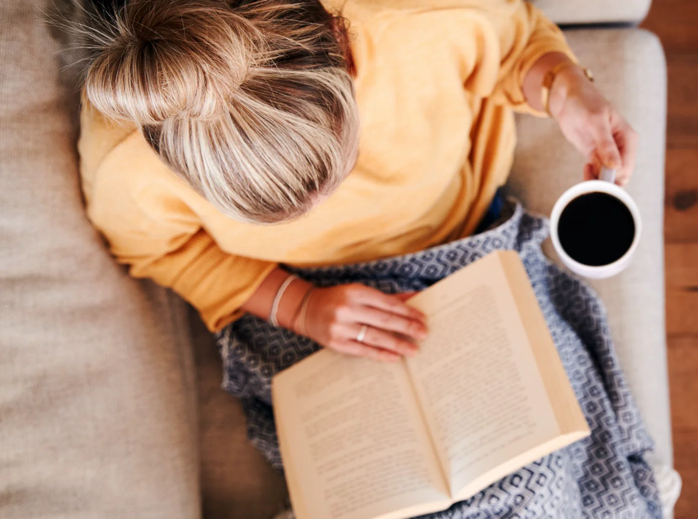 Woman reading with coffee in cozy, spotless home environment